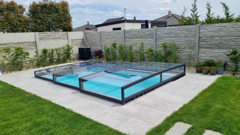 A modern, low-profile pool enclosure with an anthracite-colored frame in the garden
