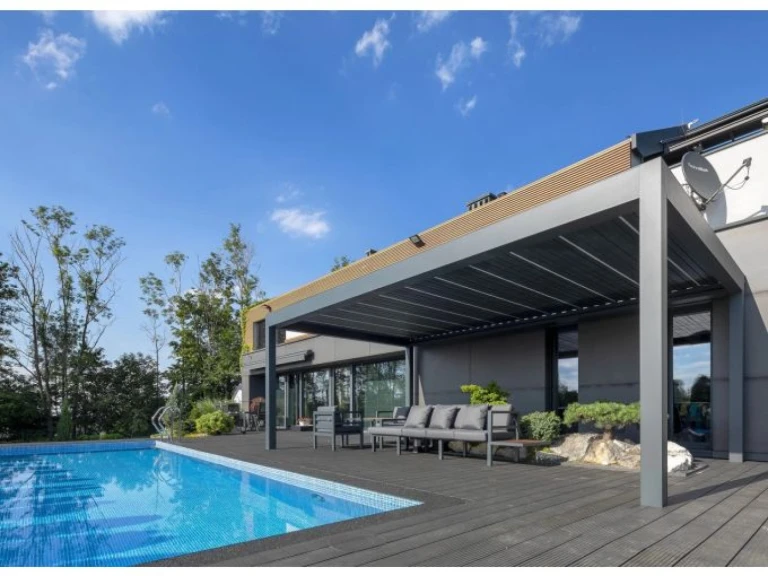A modern gray SUNBEAM 1400 bioclimatic pergola on the poolside patio with outdoor seating