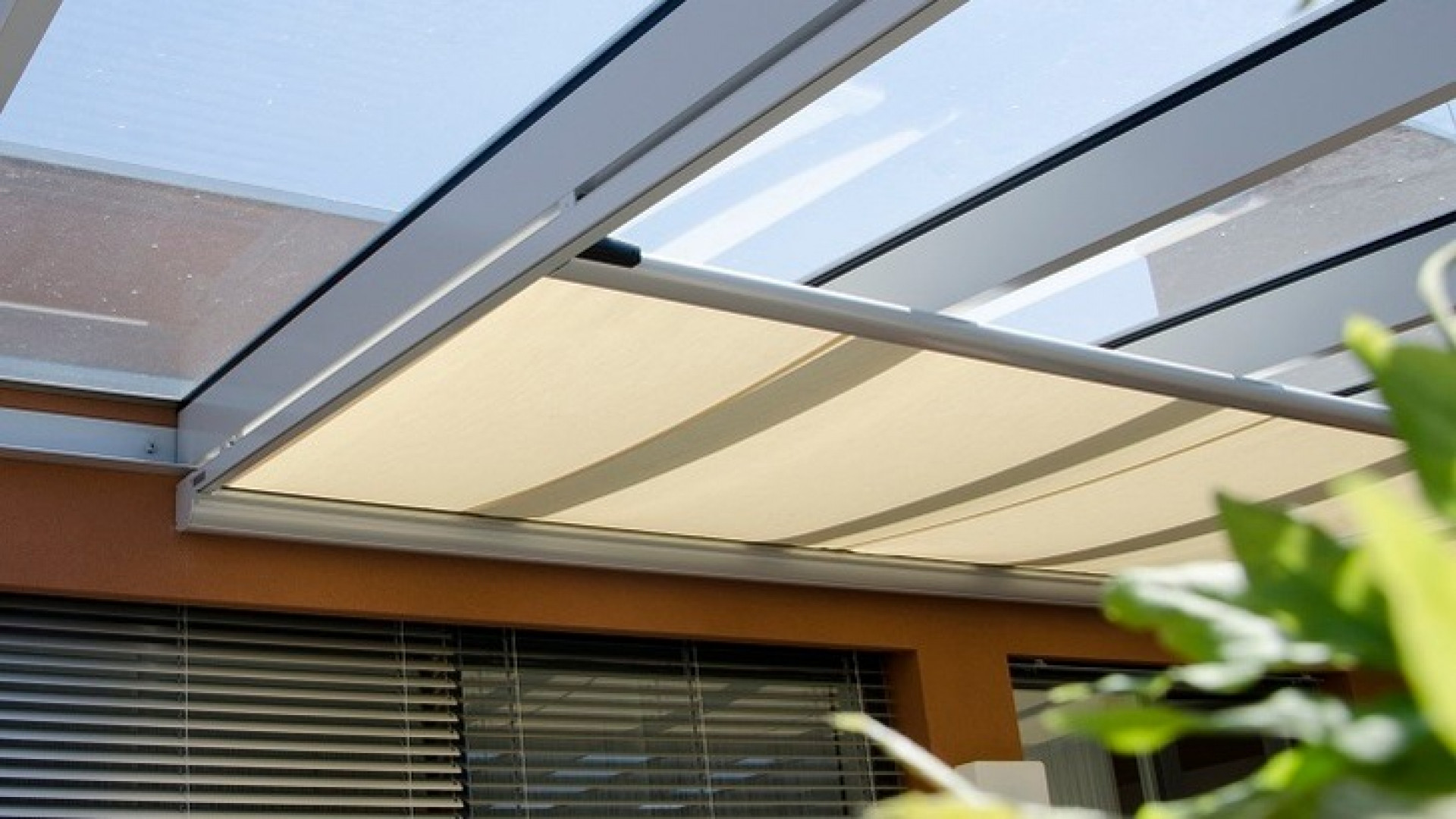 A close-up view of the partially extended light beige awning under the terrace's glass roof.