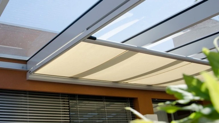 A close-up view of the partially extended light beige awning under the terrace's glass roof.