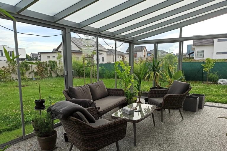 Modern balcony and patio glazing with gray furniture and a view of the garden
