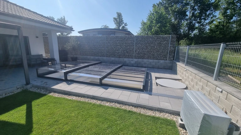 A modern, low-profile pool enclosure made of polycarbonate in the garden of a single-family home
