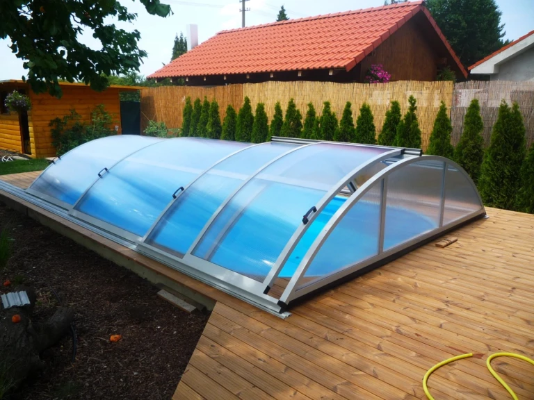 A low arched roof over the pool on a wooden deck in the garden