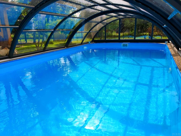 A view of the crystal-clear blue water in the pool under the arched roof in the garden