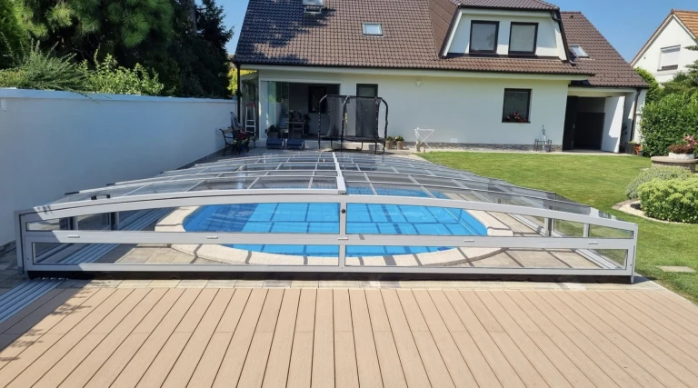 A modern, low-profile pool enclosure with translucent panels in the garden of a single-family home