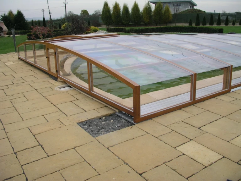 A low pool cover with a wood-grain finish and clear filling material over the outdoor pool.