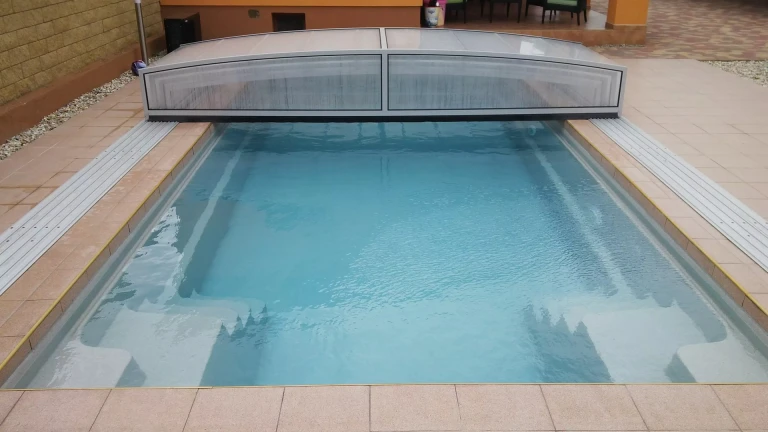 A view of the outdoor pool with clear water and a low-profile sliding roof mounted on tracks.