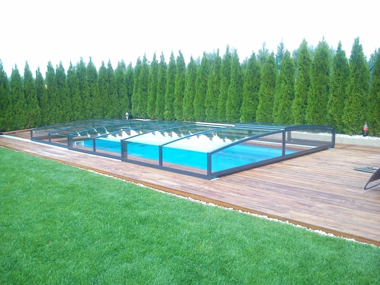 A modern, low-profile STAR pool enclosure on the patio overlooking the garden