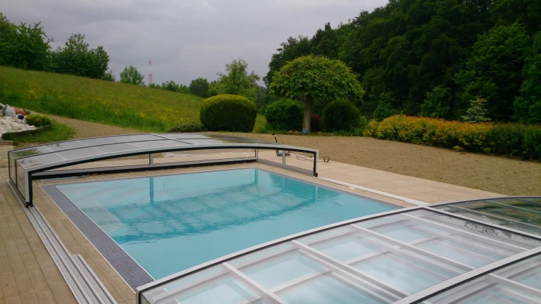 A modern, low-profile STAR pool enclosure over a sunken pool in the garden