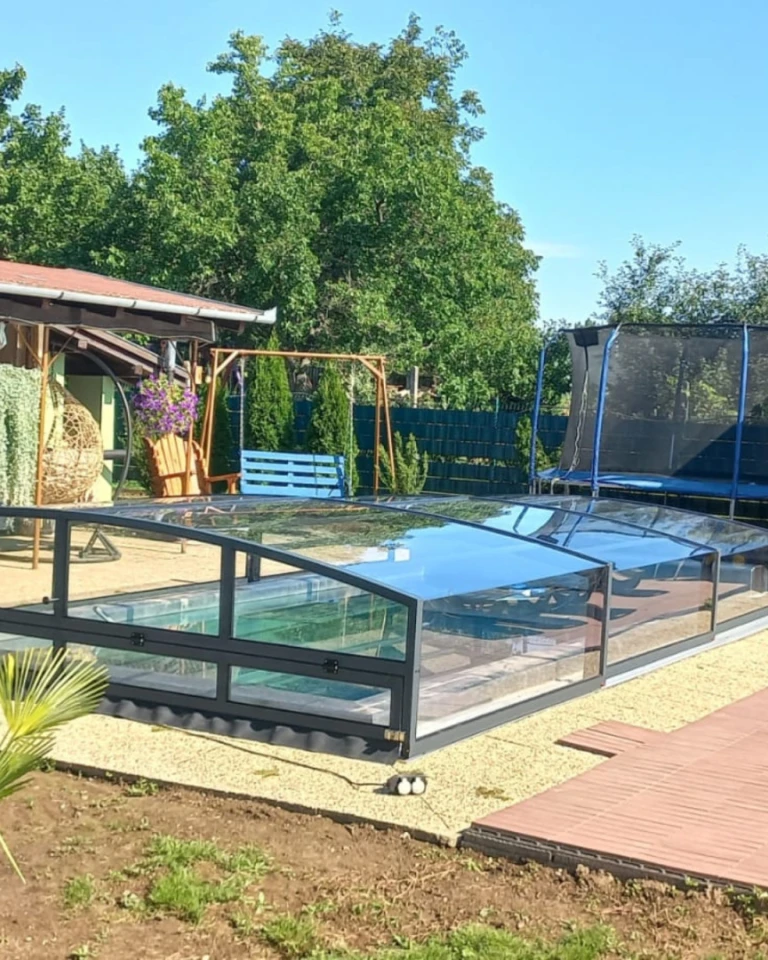 A modern, low-profile pool enclosure with an anthracite frame in the garden