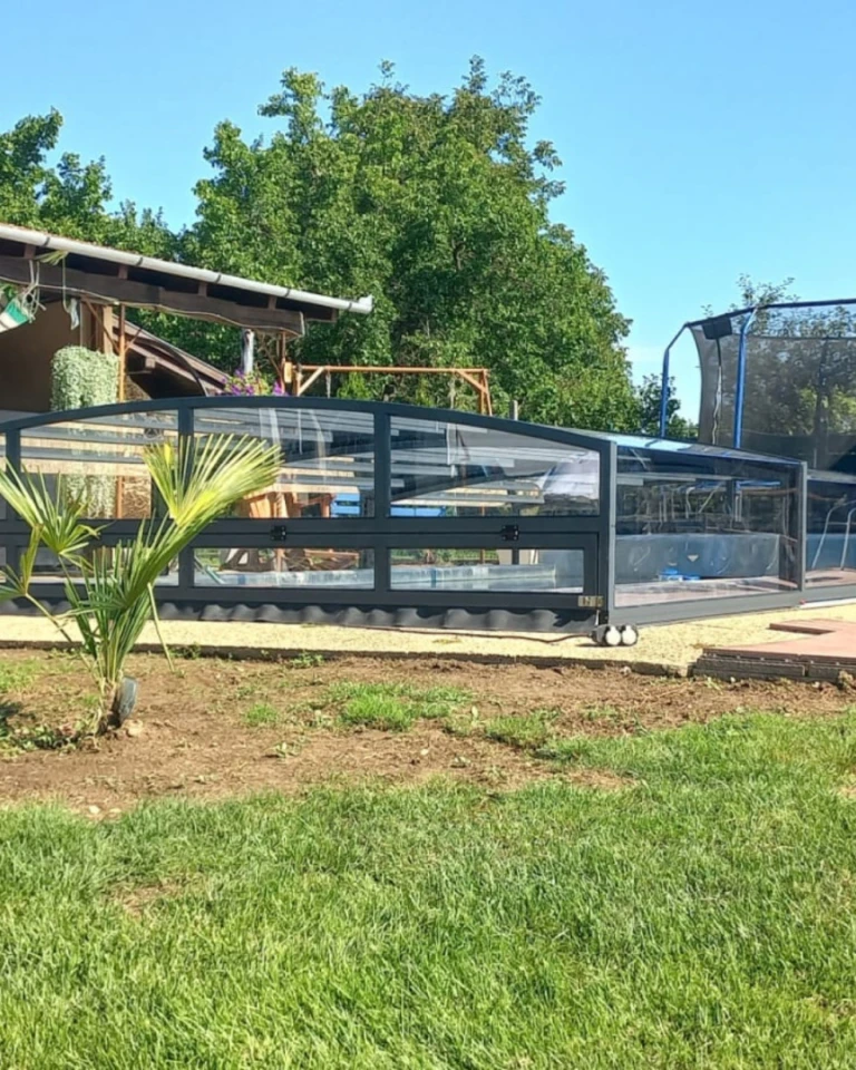 A modern, low-profile pool enclosure in anthracite in the garden