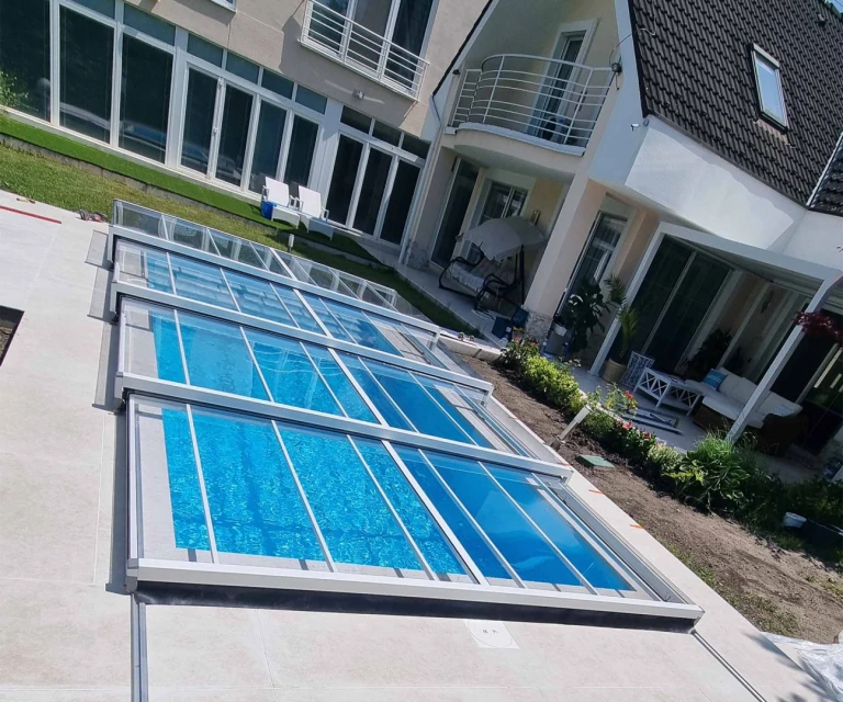 A modern, trackless EXCLUSIVE pool enclosure with a transparent panel in front of a single-family home.