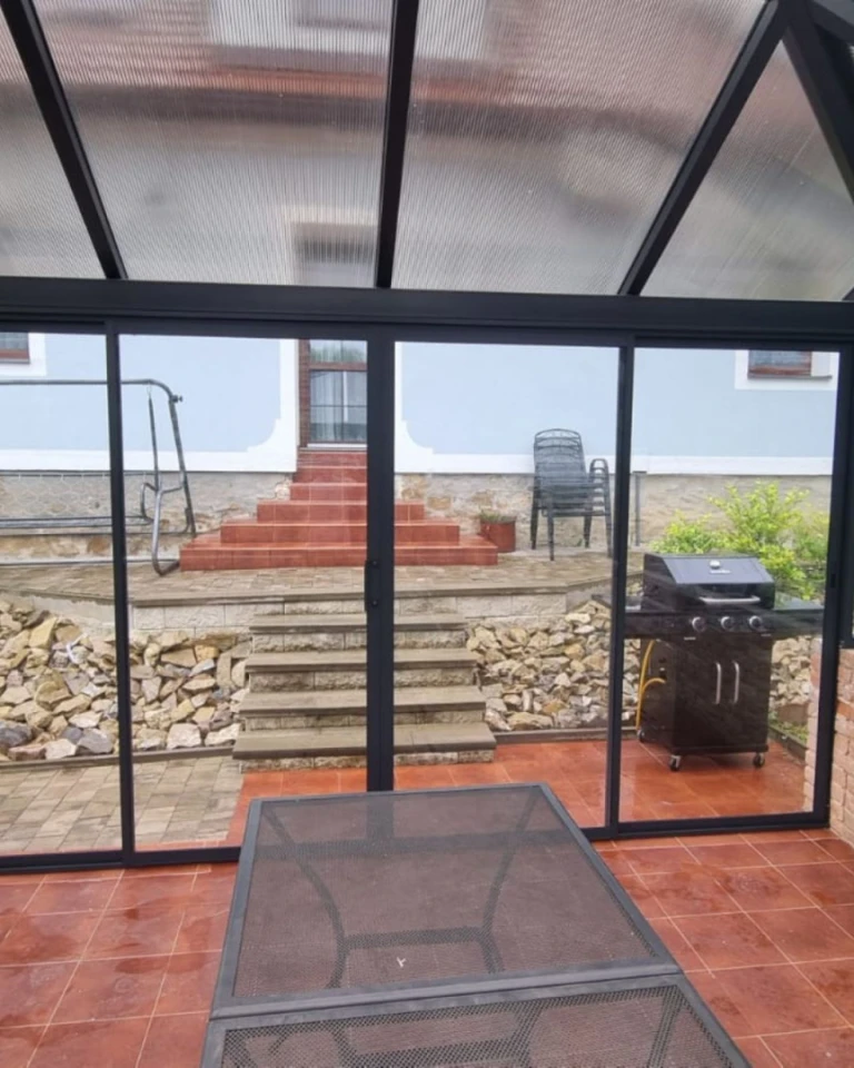 Modern sliding glass doors on the patio overlooking the garden, which features stairs and a grill.