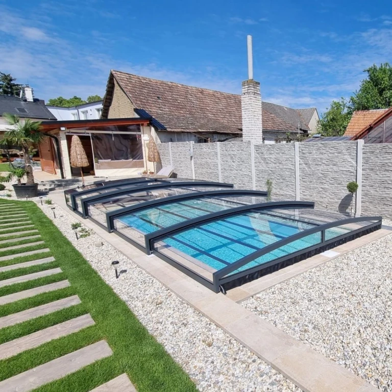 A modern swimming pool in the garden with a stylish, low-profile canopy in anthracite and a landscaped surrounding area.