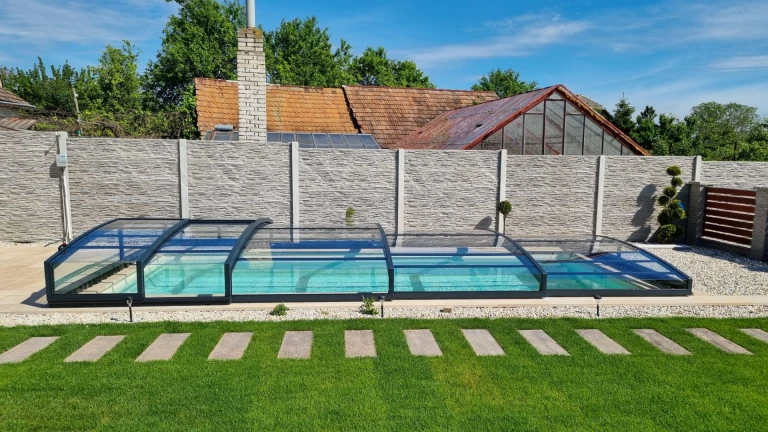 A modern, low-profile pool enclosure with an anthracite-colored frame in the garden