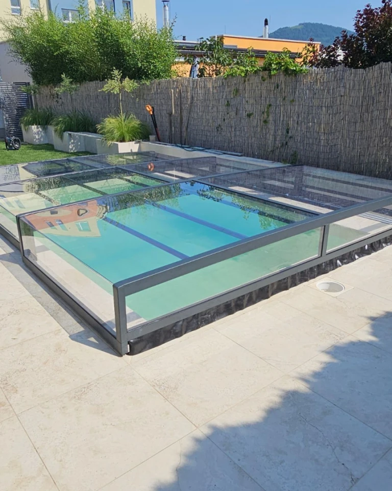 A modern, low-profile glass pool enclosure on the terrace of a single-family home