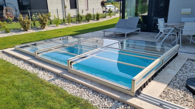 A modern, low-profile glass pool enclosure on the terrace of a single-family home in Záhorská Bystrica.