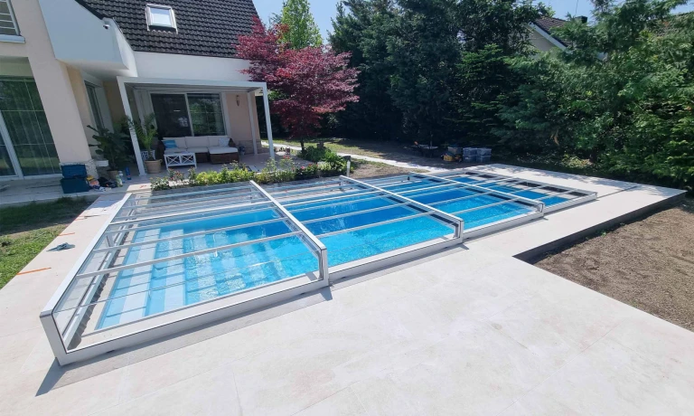 A modern, low-profile, trackless pool enclosure in the garden of a single-family home