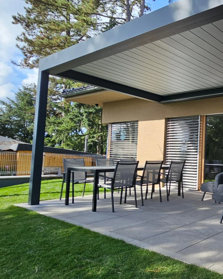 A modern bioclimatic pergola over the terrace with a dining area at a family home