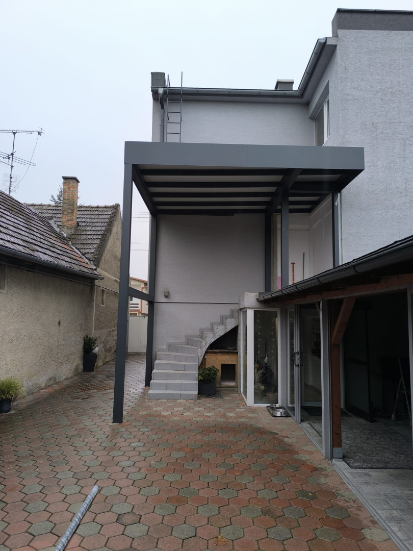 A modern, custom-made gray aluminum pergola installed on the terrace of a single-family home above the outdoor staircase.