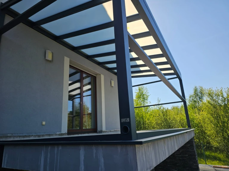 A modern aluminum pergola with a glass roof on the elevated terrace of a single-family home.