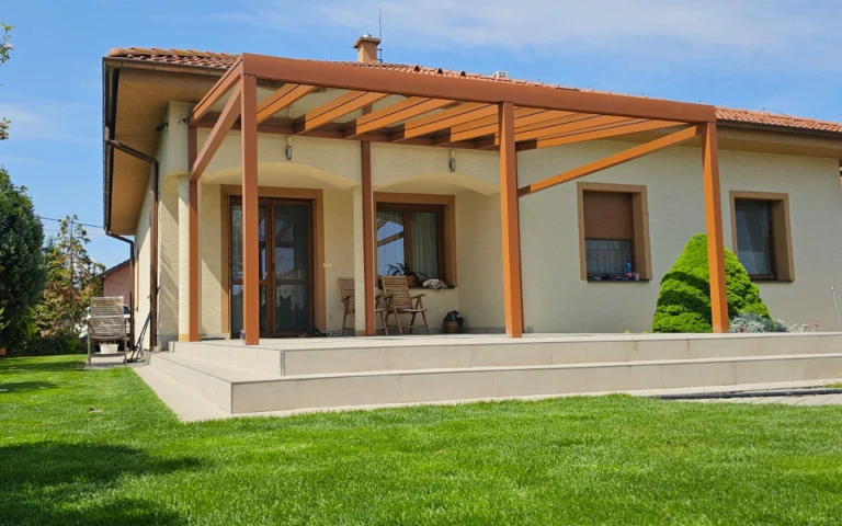 A modern aluminum pergola with a wood-grain finish installed on the deck of a single-family home