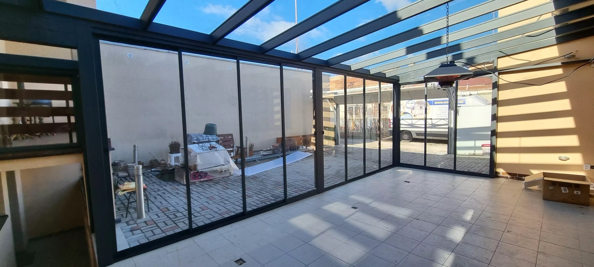 An interior view of the ROBUST glass-and-aluminum pergola with sliding glass panels on the patio of a single-family home.
