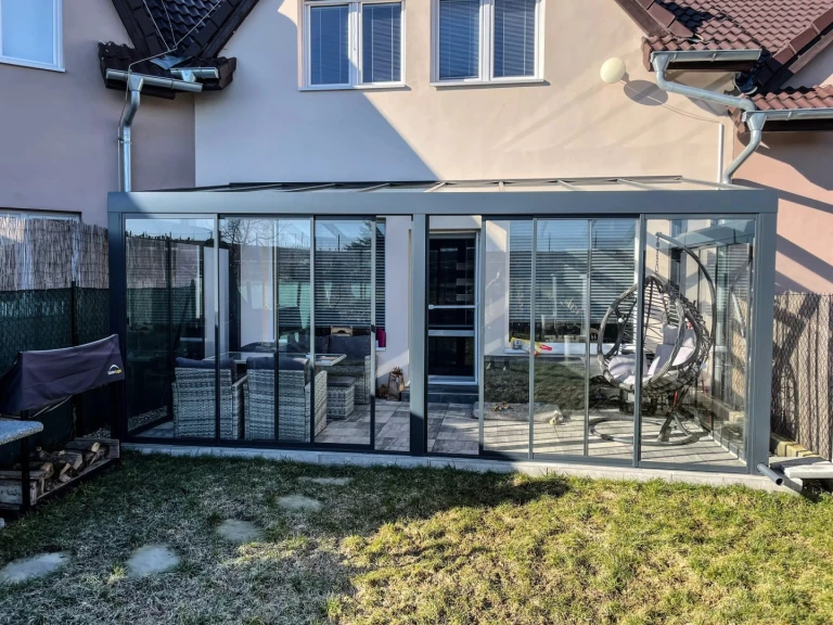 A modern ROBUST aluminum pergola with standard glazing and garden furniture in the village of Stehelčeves