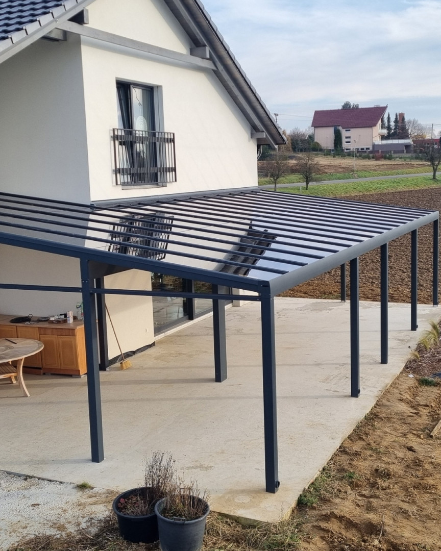 A modern dark gray aluminum pergola with a glass roof installed at a single-family home in Senec.