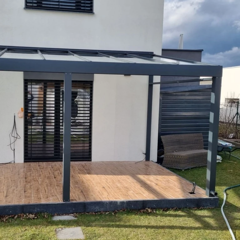 A modern, anthracite-colored aluminum conservatory structure on a terrace with a wooden floor.