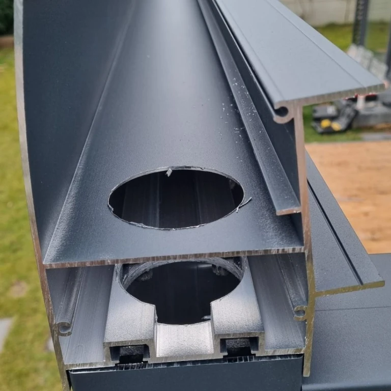 A detailed view of a cross-section of an aluminum gutter profile with a drilled hole for a chimney.