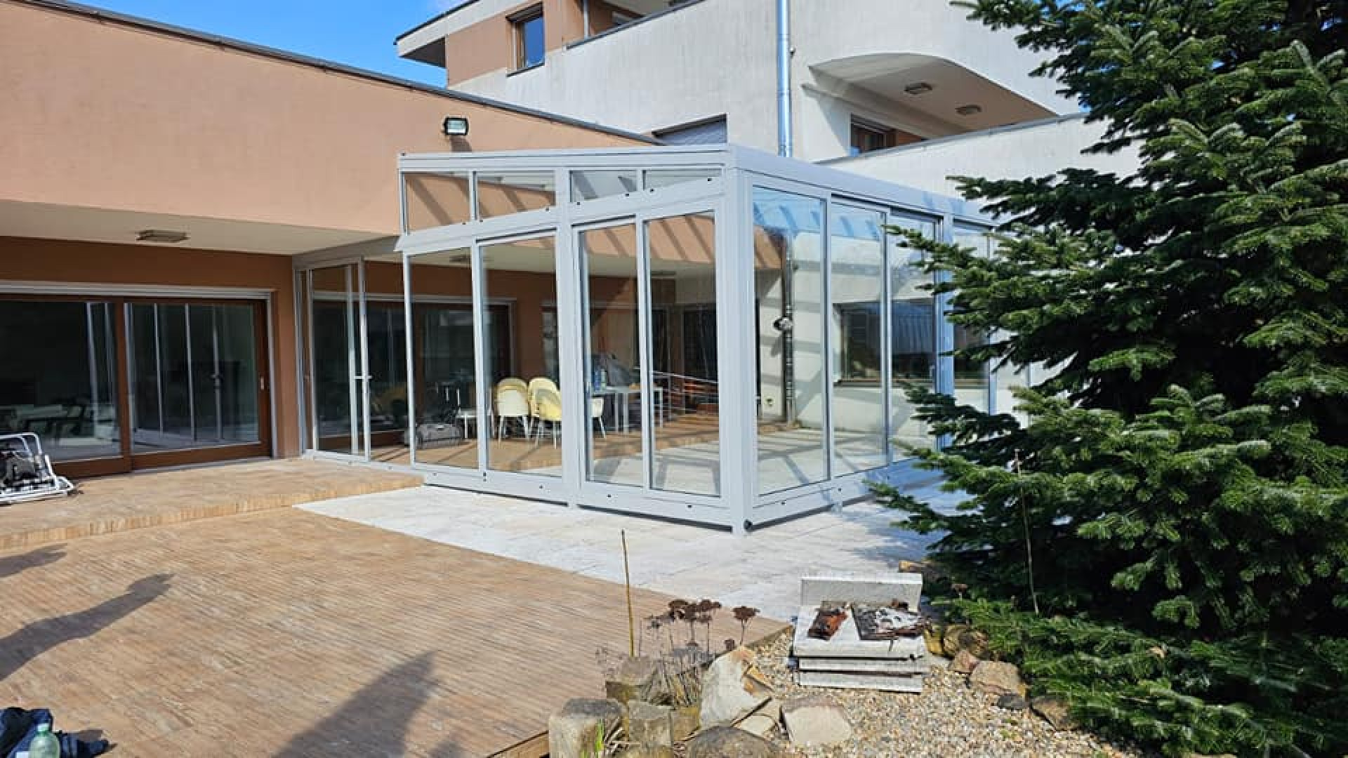 A modern aluminum sunroom with sliding glass doors attached to a single-family home