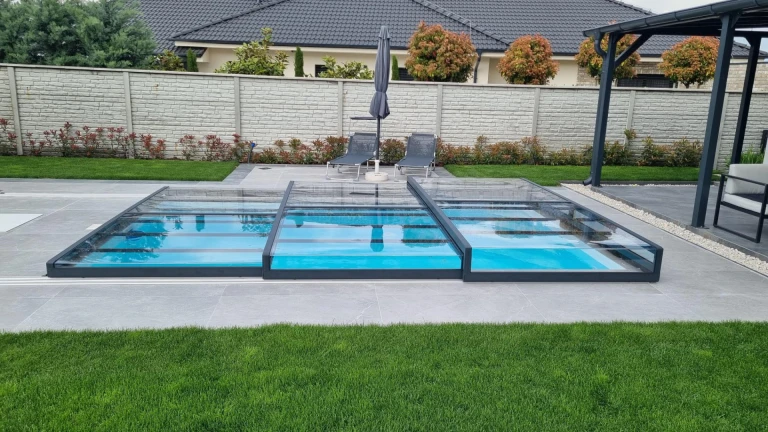 A modern, low-profile aluminum pool enclosure in the garden of a single-family home