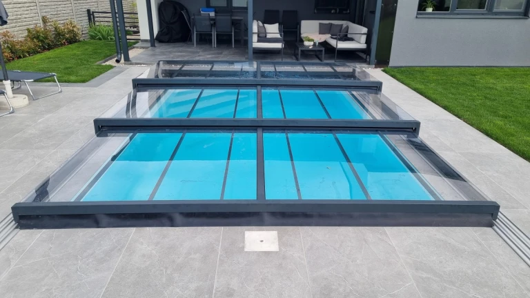 A modern, low-profile aluminum pool enclosure with a transparent panel on the terrace of a single-family home