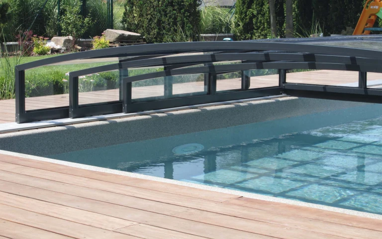 A close-up view of the low aluminum pool enclosure with rails on a wooden deck