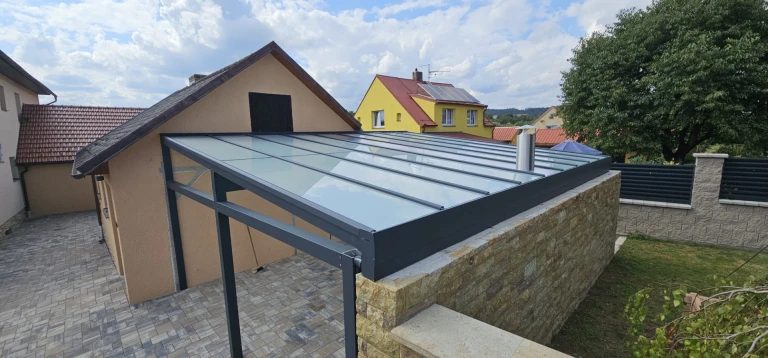 A modern patio cover with an anthracite aluminum frame and a glass roof at a single-family home