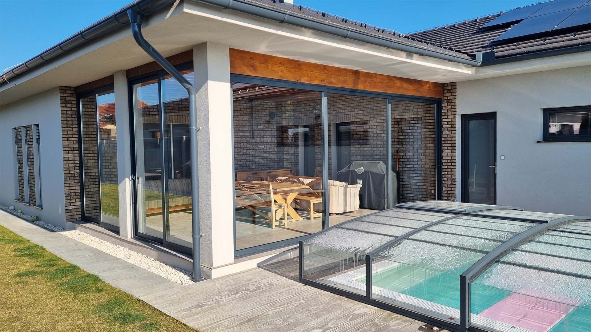 Modern, glass-paneled aluminum sliding doors on the terrace of a single-family home overlooking the pool.