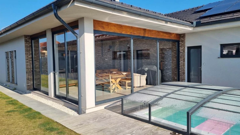 Modern, glass-paneled aluminum sliding doors on the terrace of a single-family home overlooking the pool.