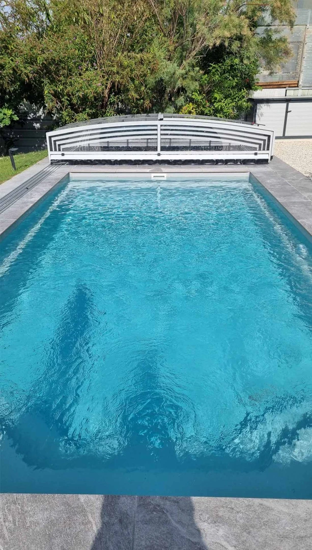 A view of the outdoor pool with the low canopy retracted at the far end of the pool in the garden