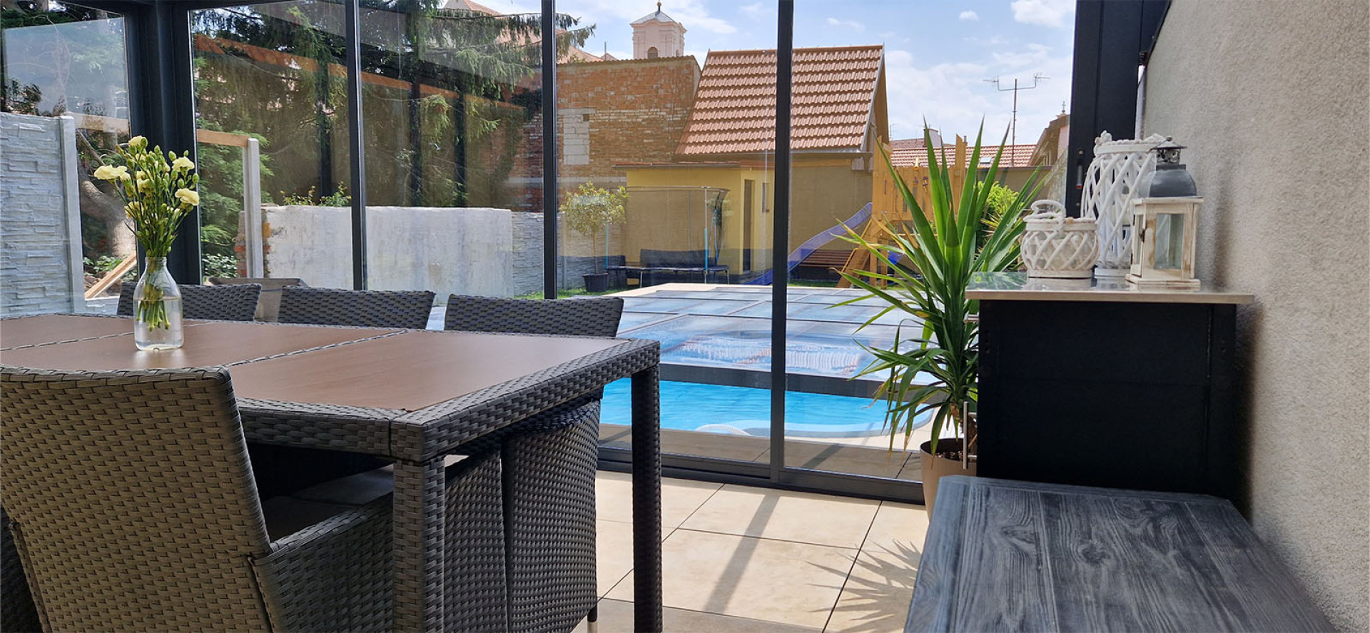 A view from inside the sunroom, with patio furniture on the terrace overlooking the pool