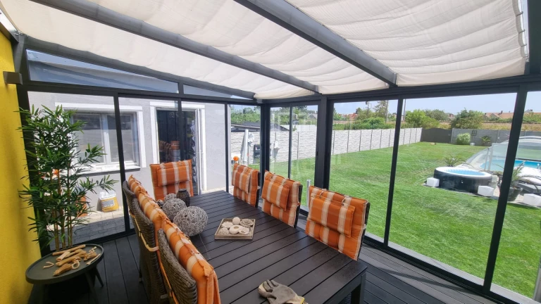 The interior of an aluminum sunroom with a dining area and a view of the garden
