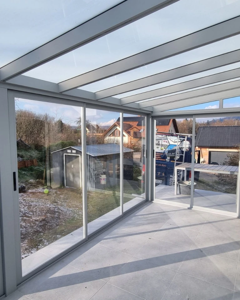 The interior of a glass-enclosed sunroom overlooking the courtyard and the surrounding houses