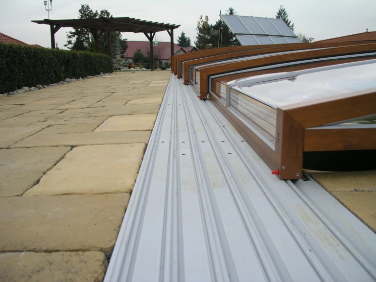 A close-up view of the rails and the structure of the pool enclosure with a wood-grain finish.