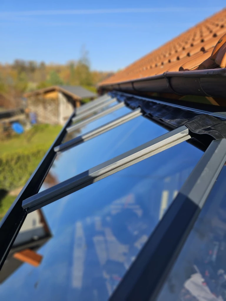 Detail of the connection between the glazed pergola roof and the house wall beneath the eaves