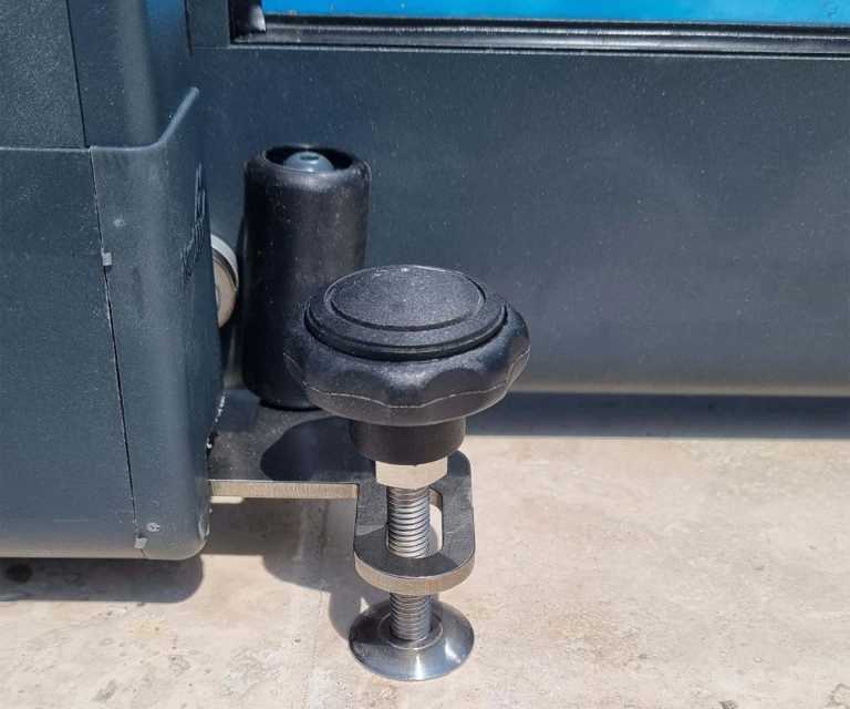A close-up view of the anchoring mechanism and locking screw of the pool cover on the pavers.