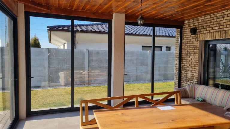 An interior view of the aluminum-framed terrace with sliding doors and a view of the garden