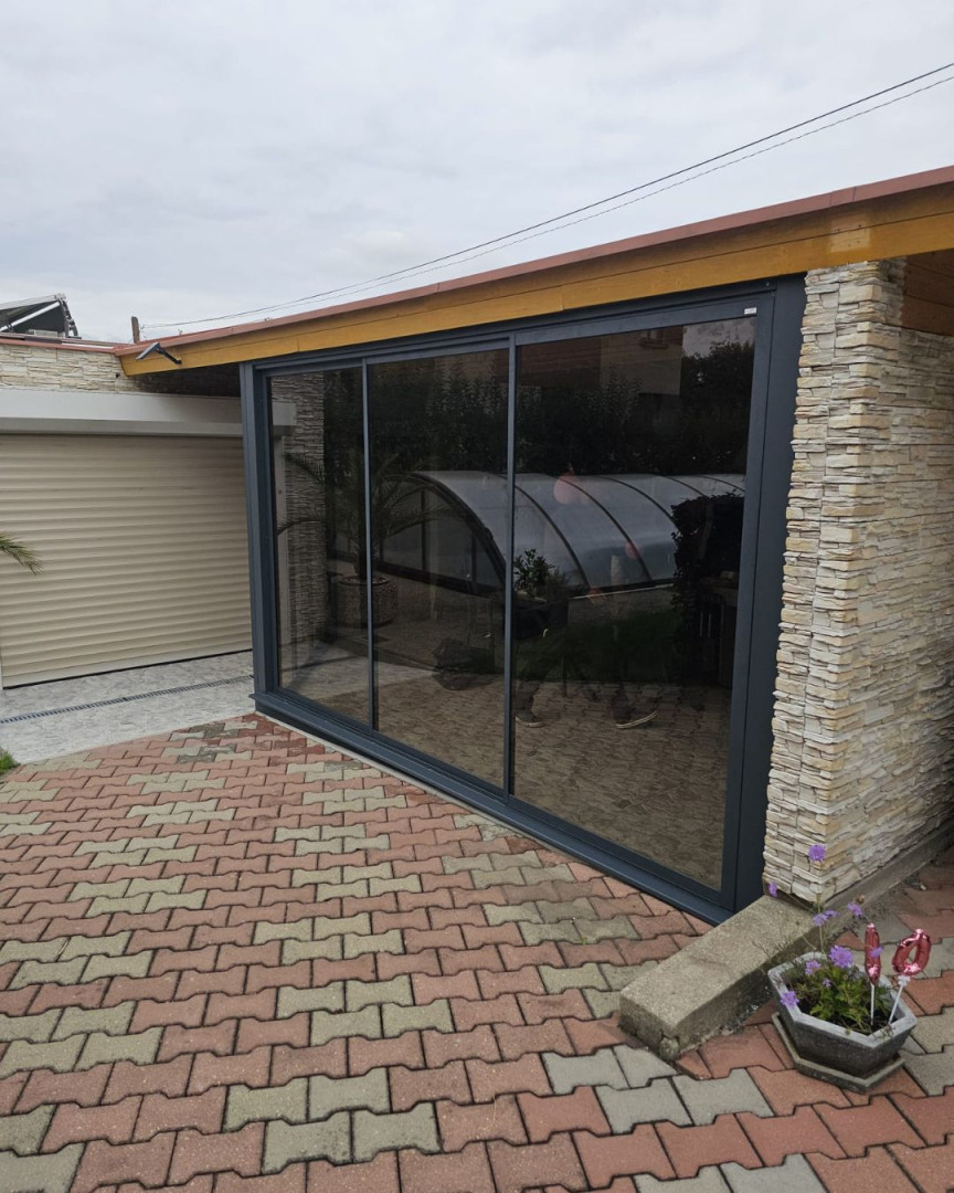 Modern sliding glass doors on the patio with an anthracite frame and stone cladding.