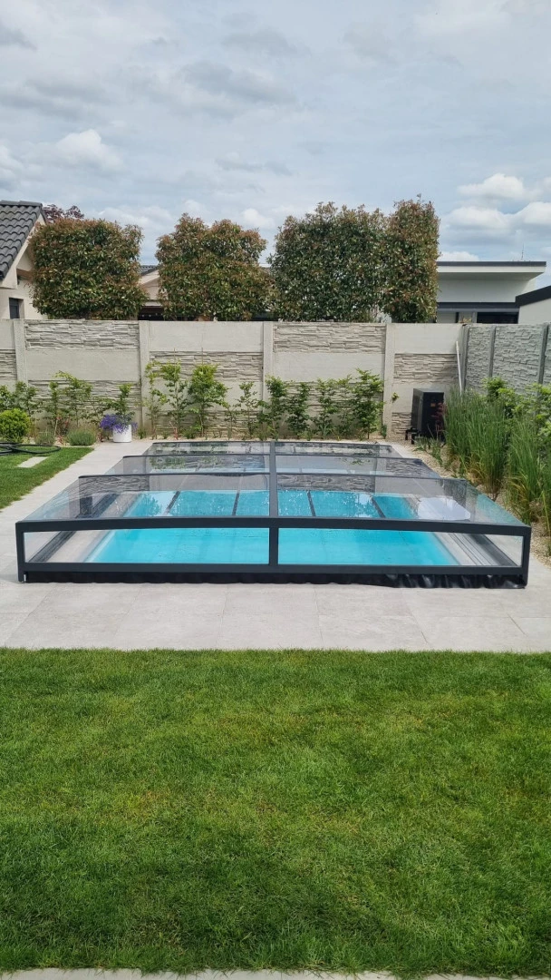 A low, modern pool enclosure in anthracite in the garden of a single-family home.