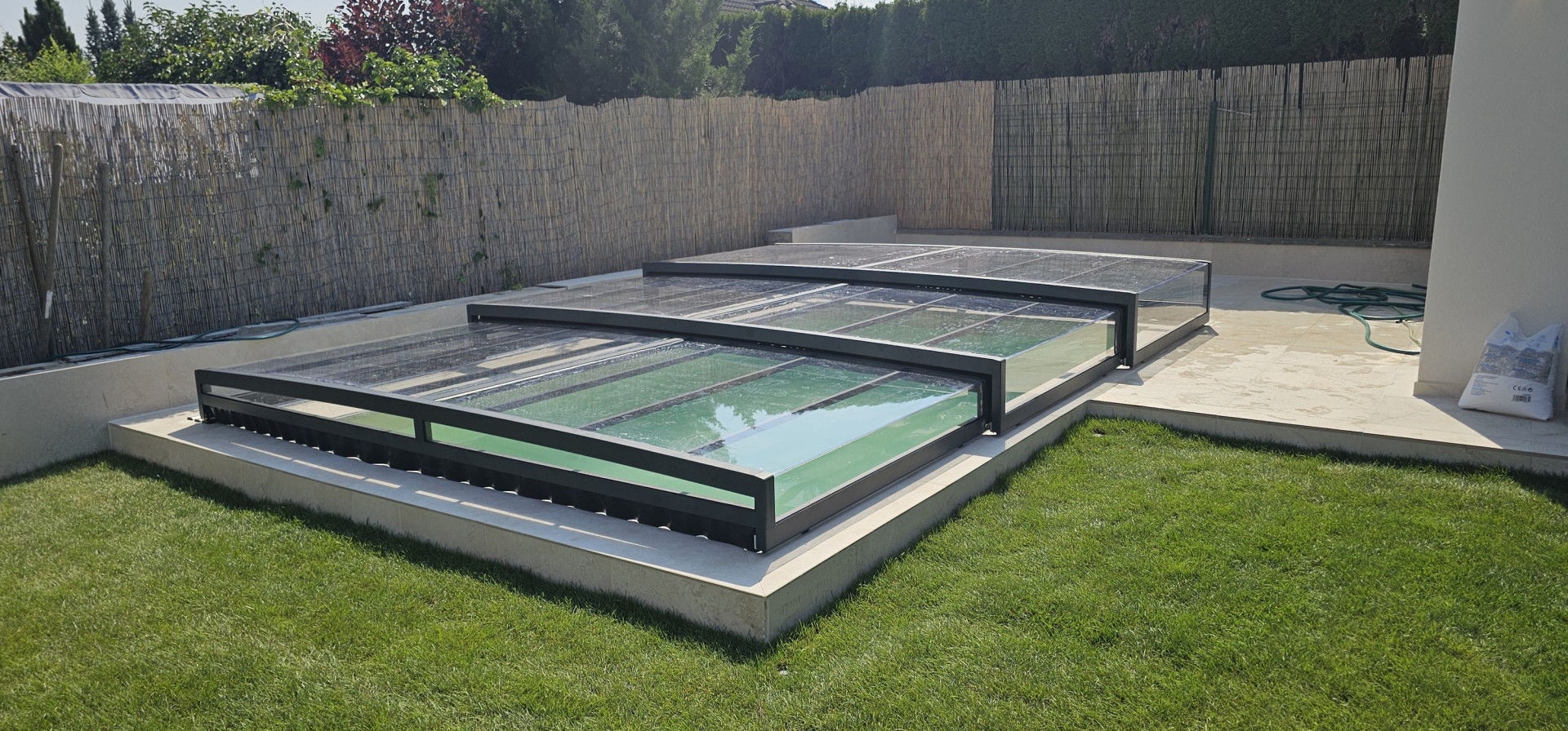 Low-profile anthracite EXCLUSIVE pool cover in a garden near Žilina