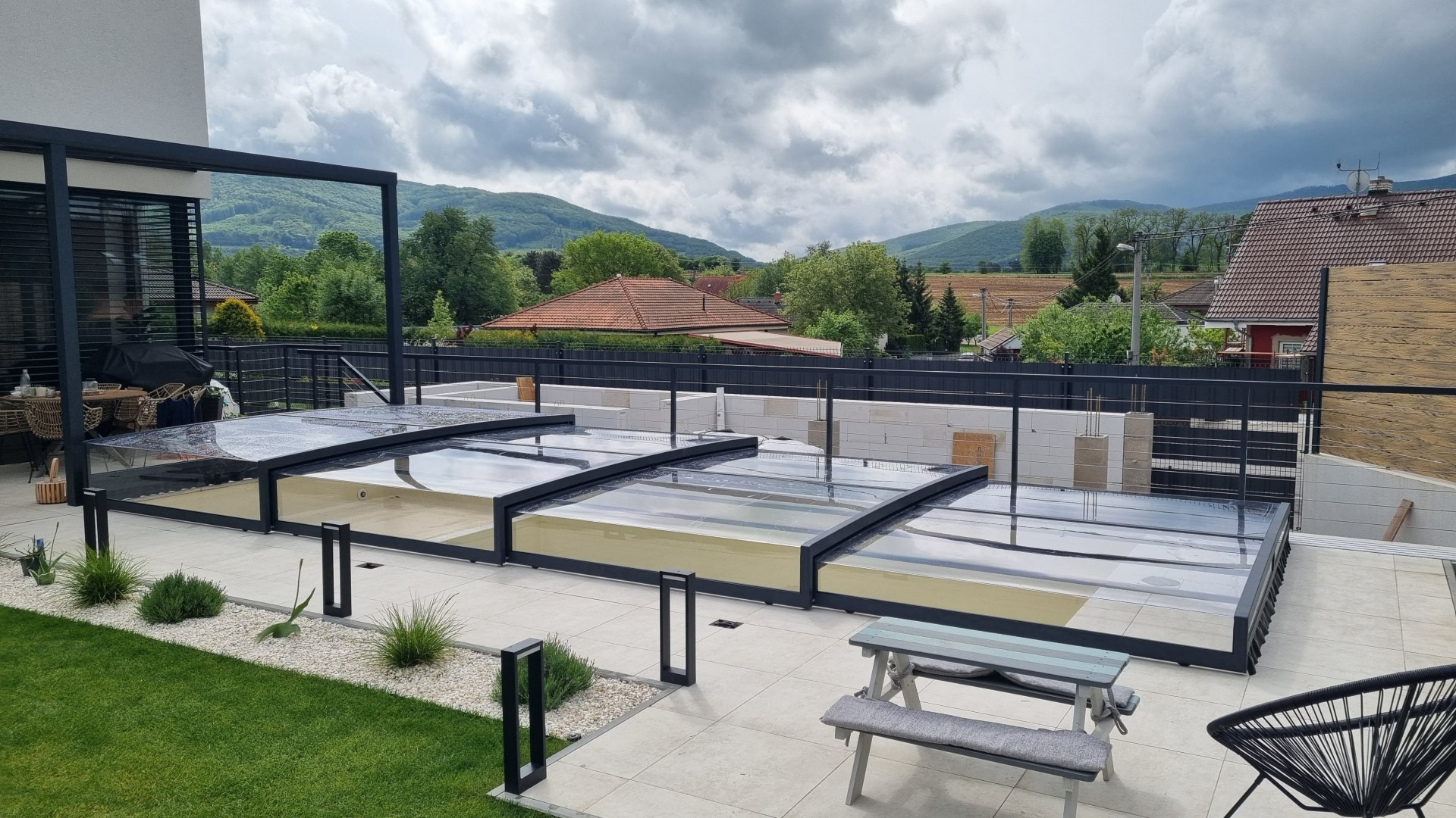 Modern, low-profile EXCLUSIVE pool enclosure with an anthracite-colored frame on the terrace of a single-family home